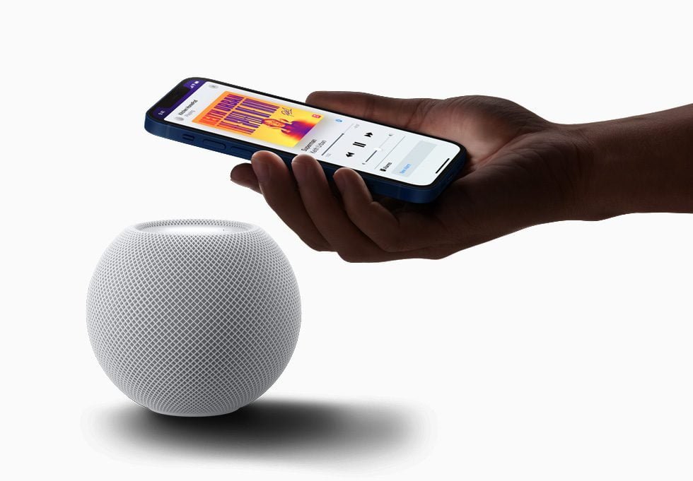 a hand holding a phone above a round white ball